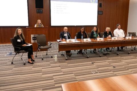 Moderators seated and a presenter standing at the podium at the CPFP Fall Symposium 2024