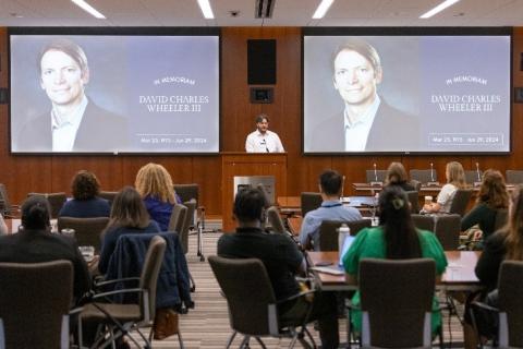 A memorial slide honoring the late David Wheeler in the background with participants seated at the CPFP Fall Symposium 2024 in the foreground.