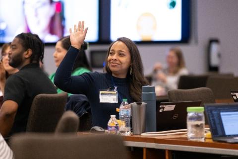 Nyahne Bergeron seated at a table, smiling with her arm raised.